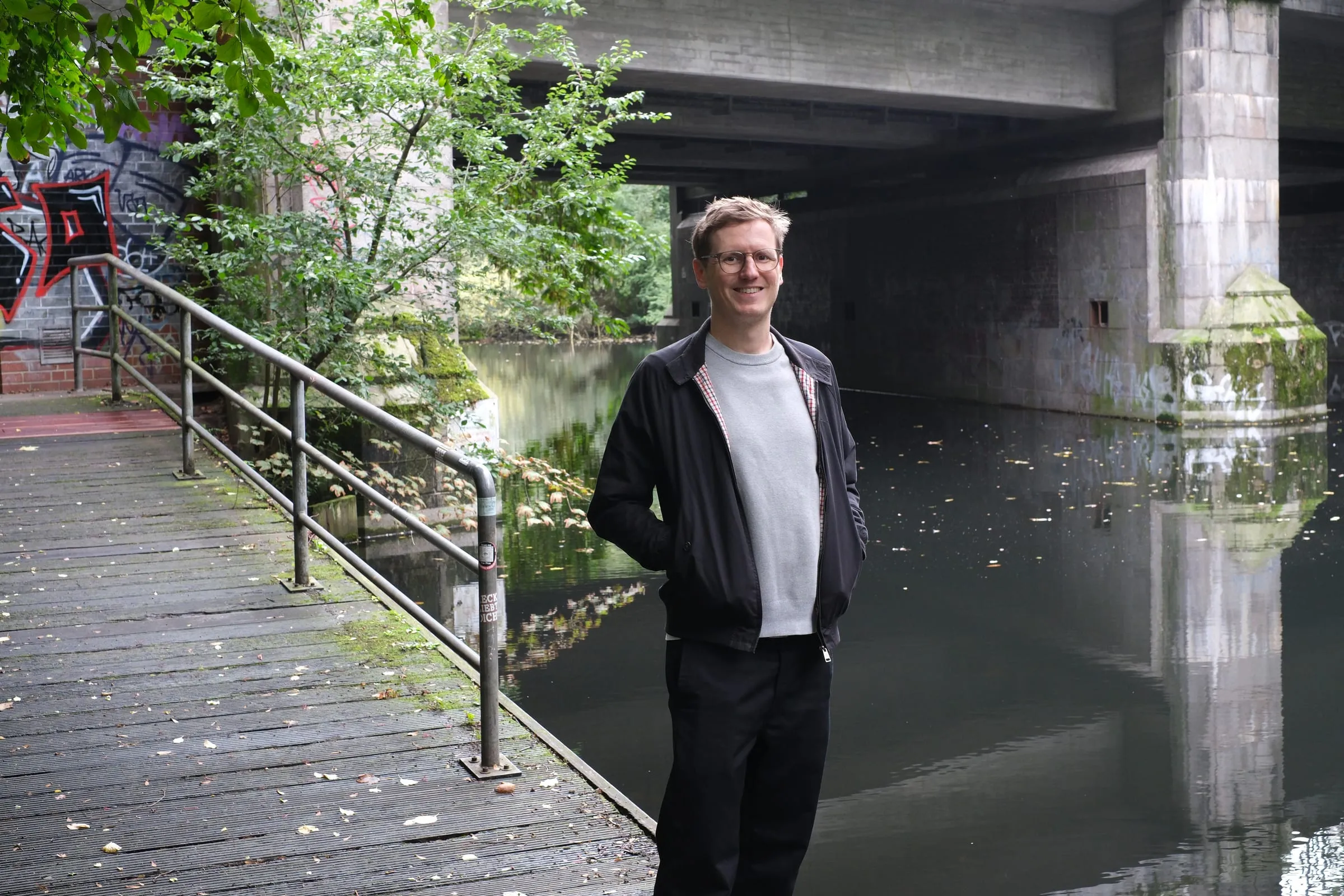 Jan Hoppe by a canal under a bridge in Hamburg